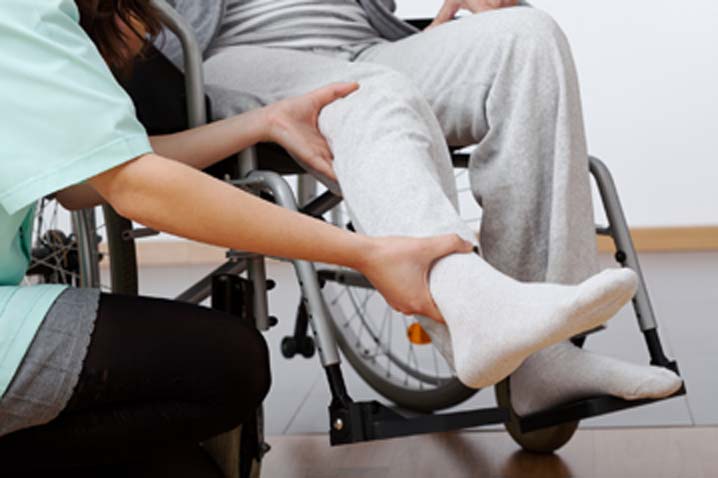 man in wheelchair with doctor holding leg