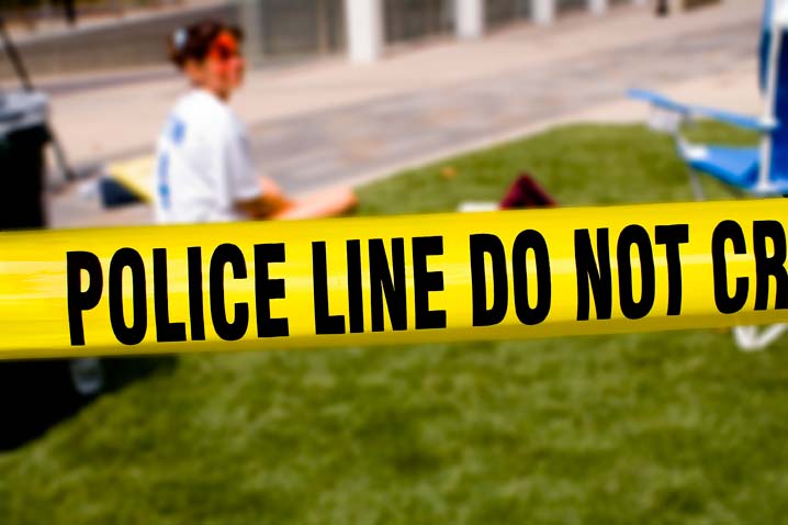 injured girl sitting on grass with police line tape